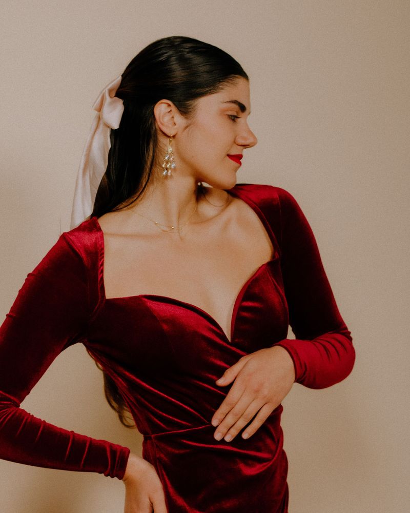 Model in a deep burgundy velvet dress with a sweetheart neckline and statement earrings in a studio