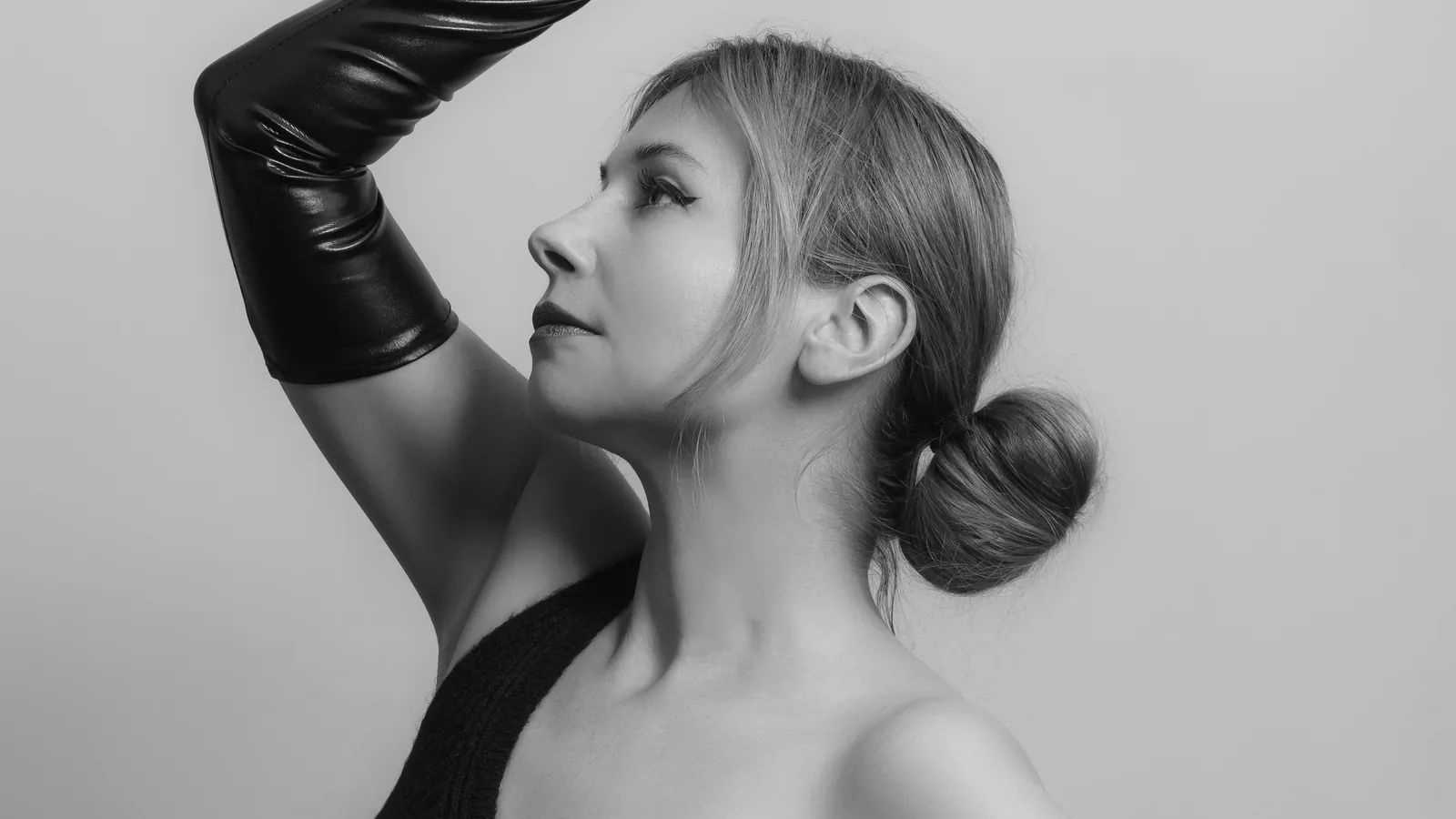 Black-and-white studio portrait of a model in long black leather opera gloves and a one-shoulder top