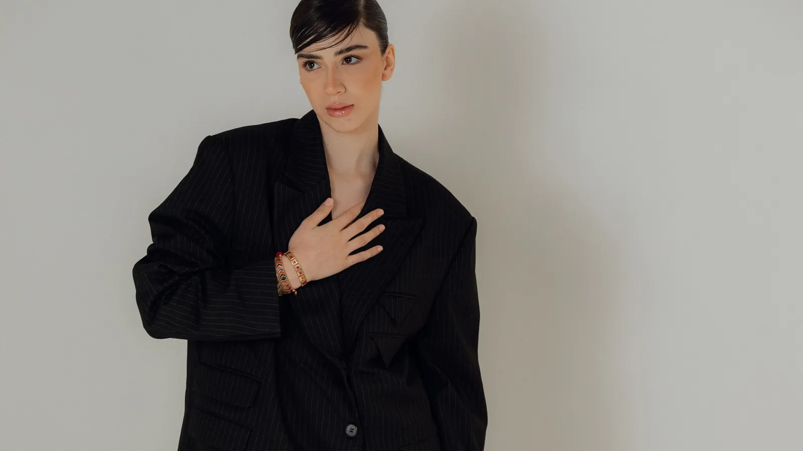 Model in an oversized black blazer with burgundy tights, posing against a neutral studio background